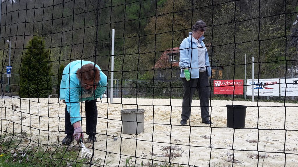 Der Sand im Volleyballfeld wird von Gras und Sämlingen befreit